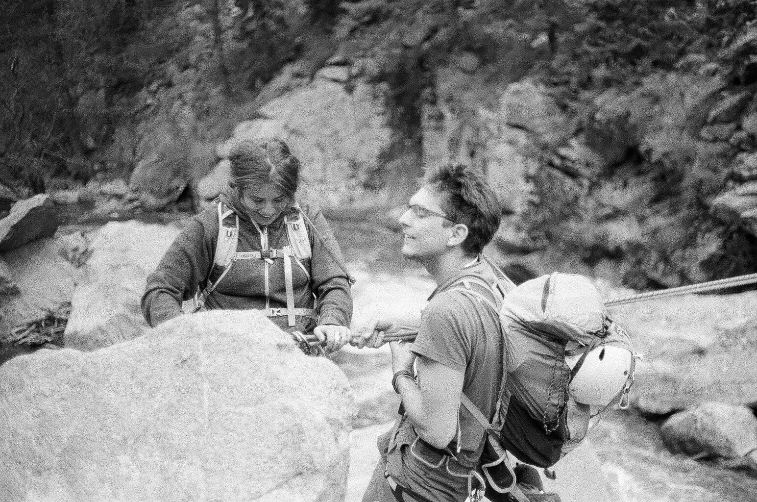 Two friends use essential climbing accessories to cross a river.