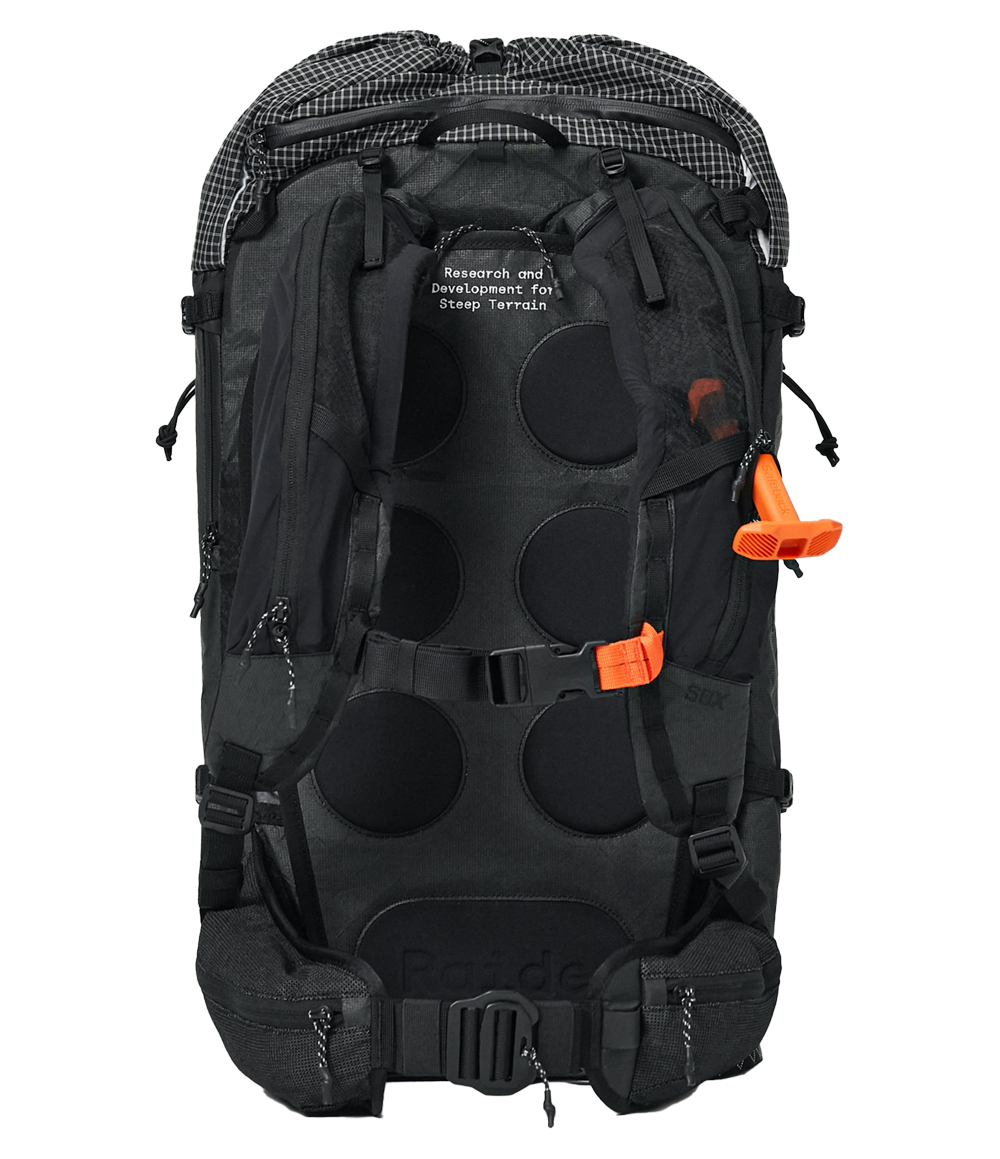 Raide SB 40L backcountry ski pack in Black with checkered roll-top closure, orange SBX system buckles, and 'Research and Development for Steep Terrain' text on front panel