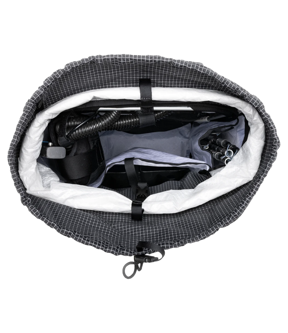 Raide SB 40L backcountry ski pack in Black with white gridded ripstop fabric, shown from above with roll-top open to reveal main compartment packed with avalanche probe, climbing skins, and other backcountry gear