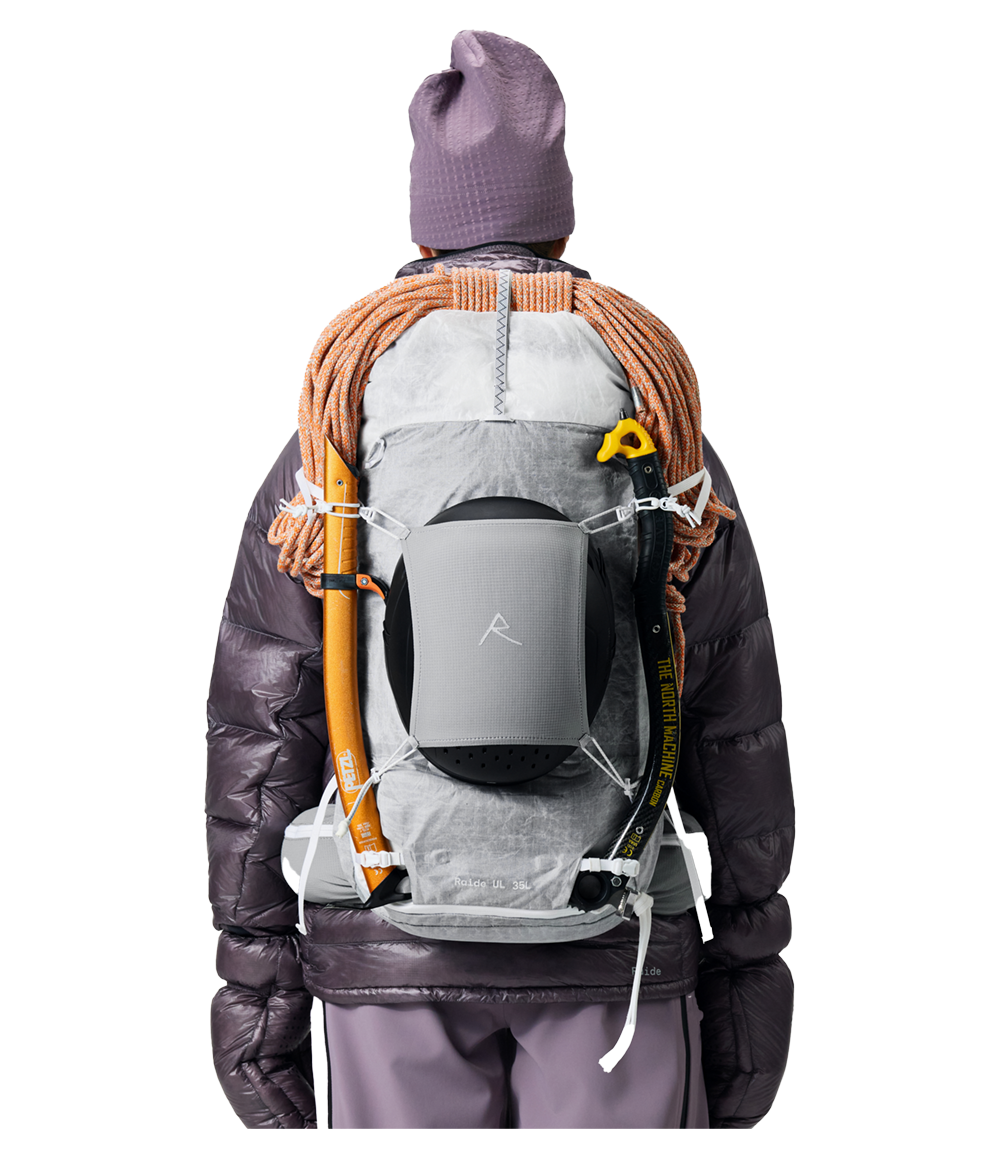 Raide UL 35L backcountry ski pack in light grey with back panel access, shown from rear with ice axe and rope attached, featuring removable frame and rolltop closure