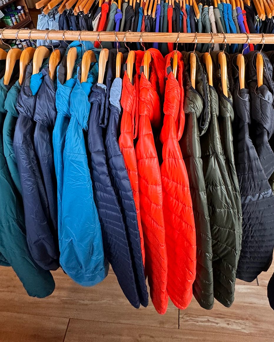 A rack of insulated outer layers hangs at Alpenglow Sports