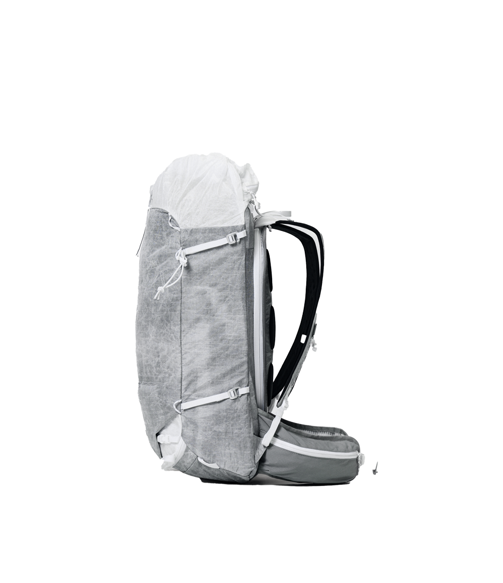 Raide UL 35L backcountry ski pack in light grey ALUULA fabric, side profile showing rolltop closure, diagonal ski carry straps, black shoulder straps, and padded hipbelt