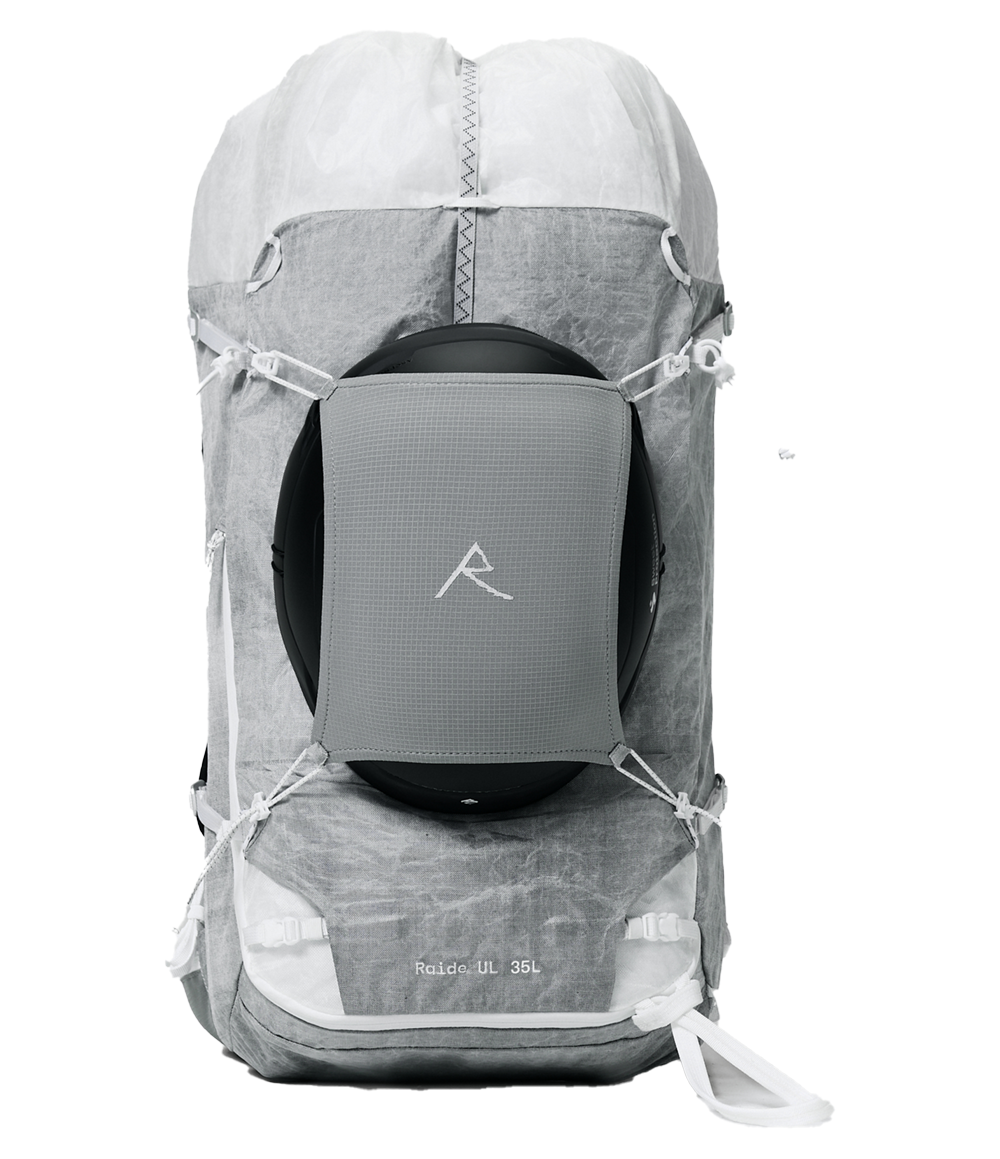 Raide UL 35L backcountry ski pack in light grey with white rolltop closure, back panel access zipper, diagonal ski carry straps, and ultralight ALUULA fabric construction